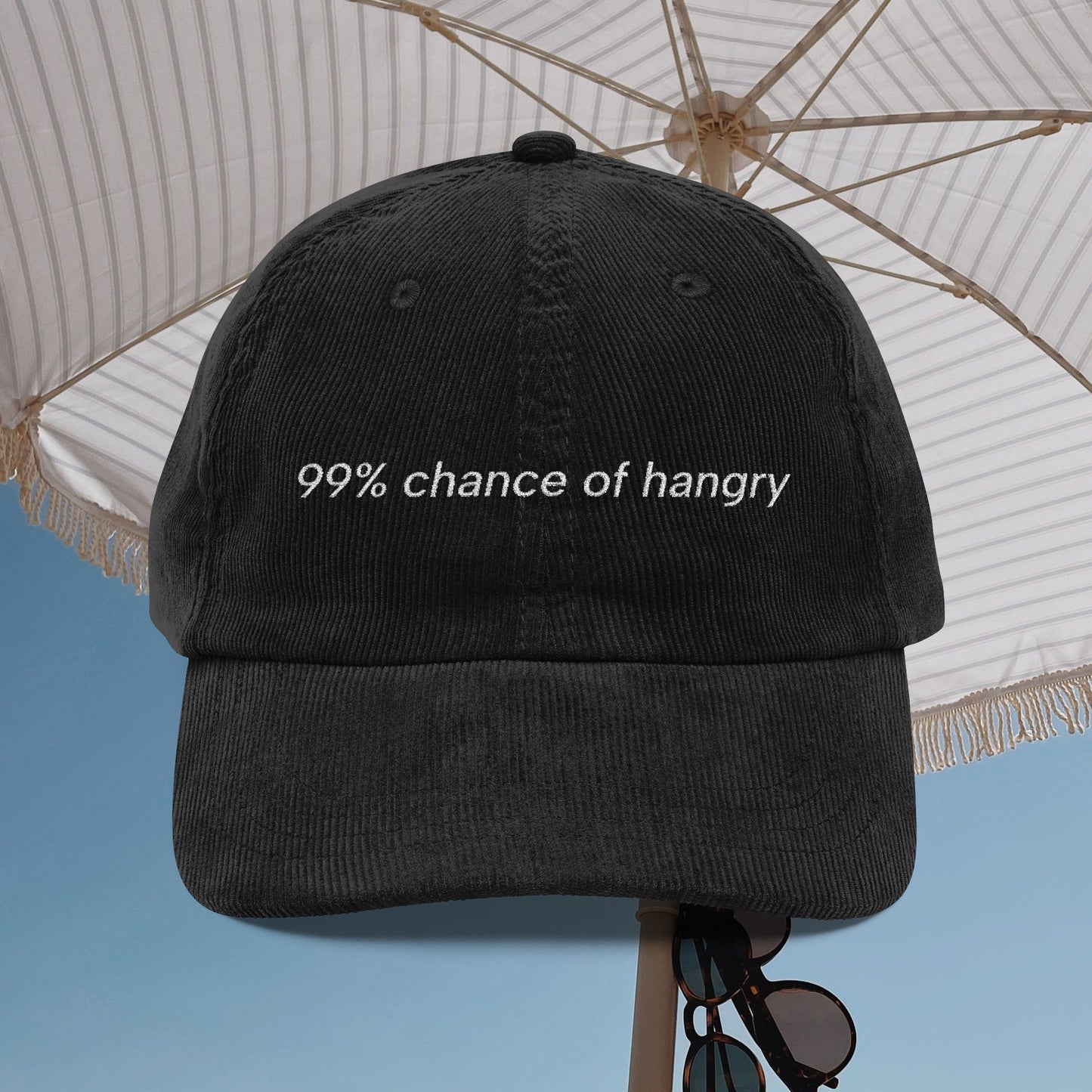 Black corduroy dad hat with '99% chance of hangry' embroidered text under an umbrella