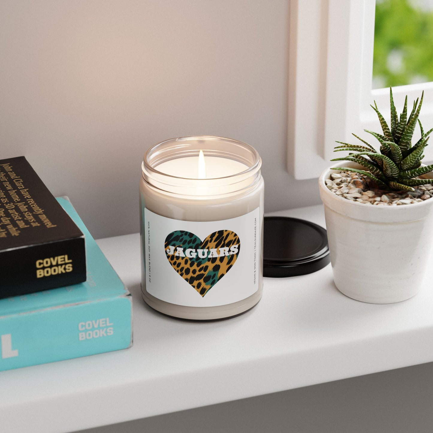 Teal Sundaze candle with a jaguar print heart design with "Jaguars" in white text on a shelf with books and a plant