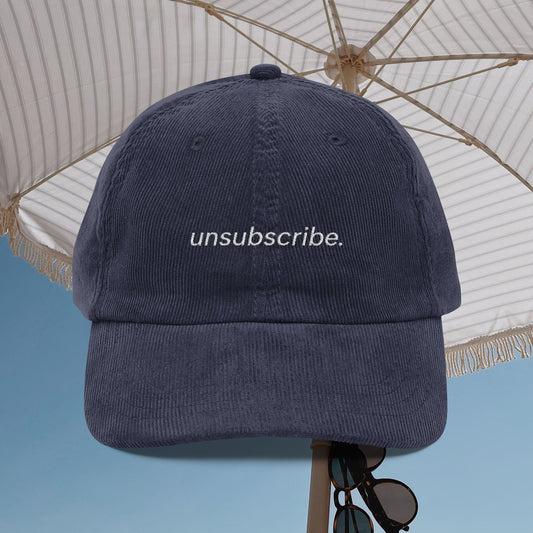 Navy blue cap with 'unsubscribe.' text under a white umbrella