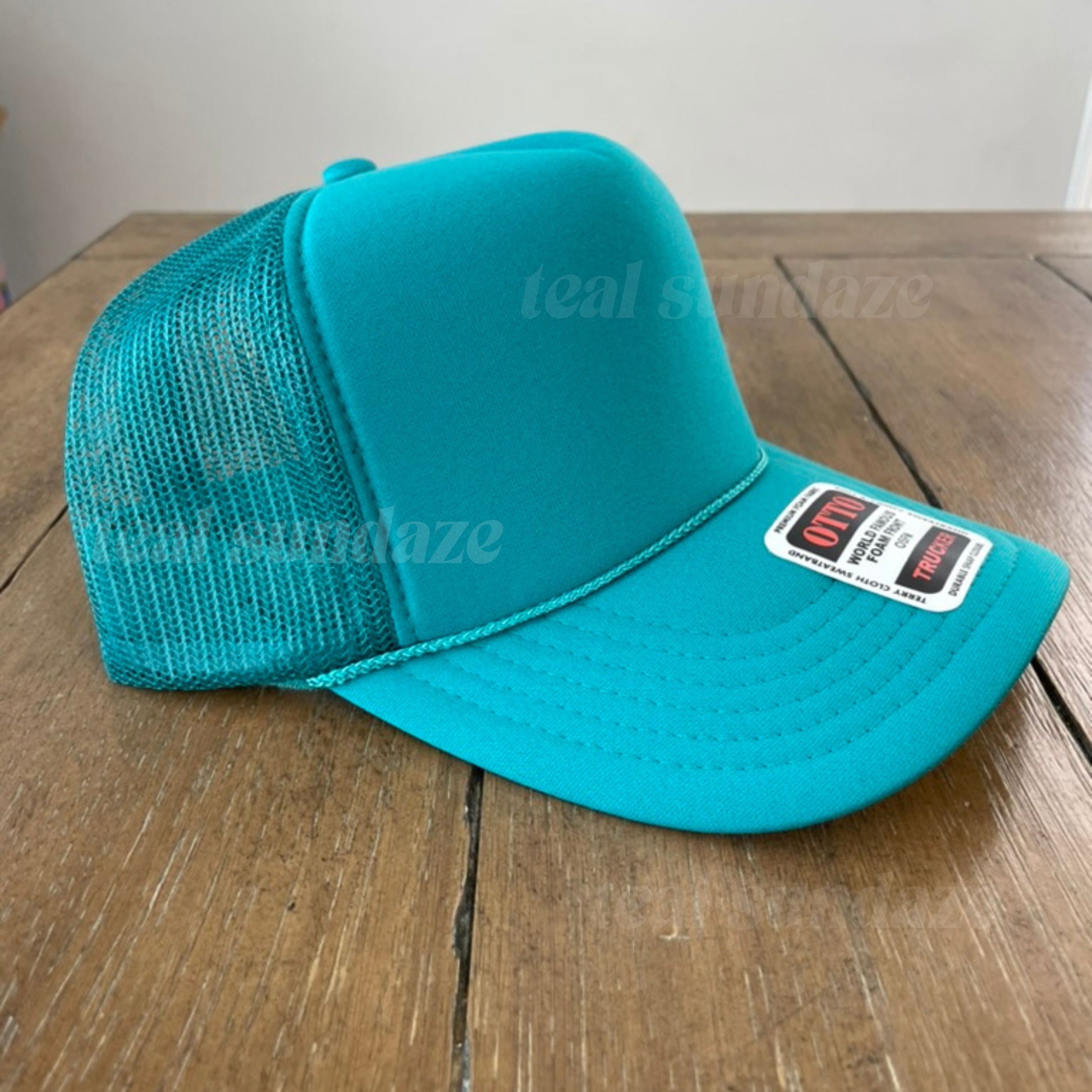 Teal mesh cap with a brand label on a wooden surface