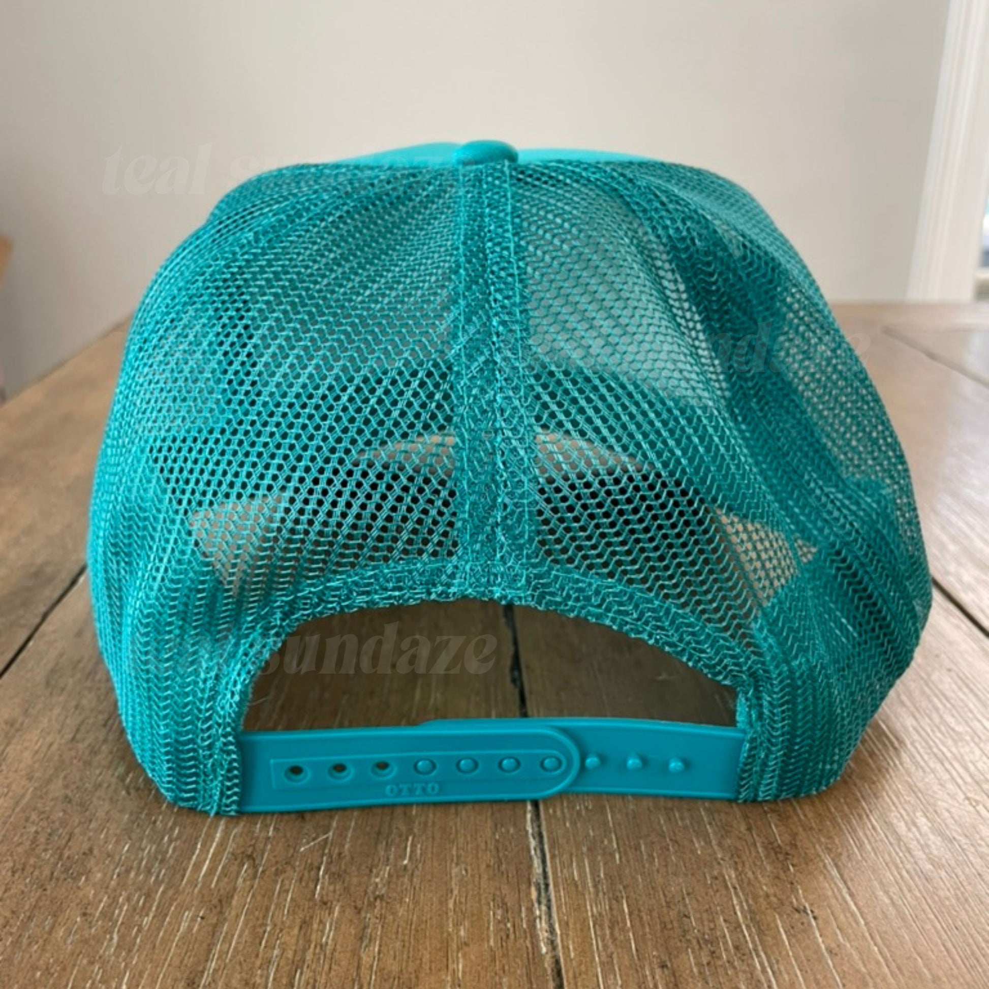 Teal mesh cap on a wooden surface